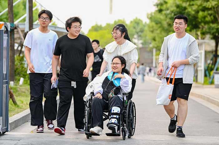 Several students help push their physically challenged classmate out of an exam venue after the national college entrance examination in Suqian, east China's Jiangsu province, June 9, 2025.