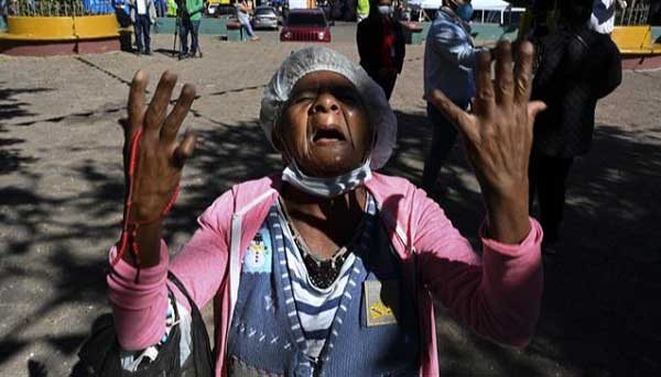 An elderly woman prays at an improvised altar with the image of the Virgin of Suyapa, patron saint of Honduras. 