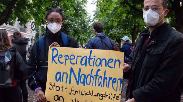 Protesters hold a sign reading "Reparations to descendants instead of 'development aid' to Namibia" at a demonstration in Berlin on May 28. 