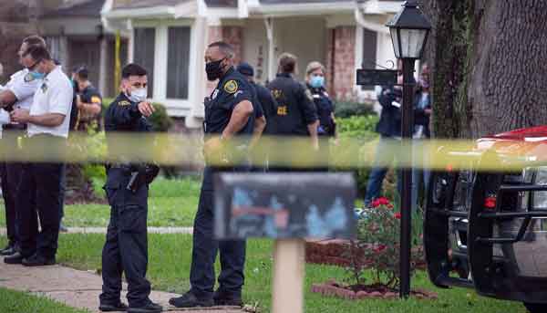 Police officials stand outside 12200 Chessington Drive in southwest Houston, Texas.