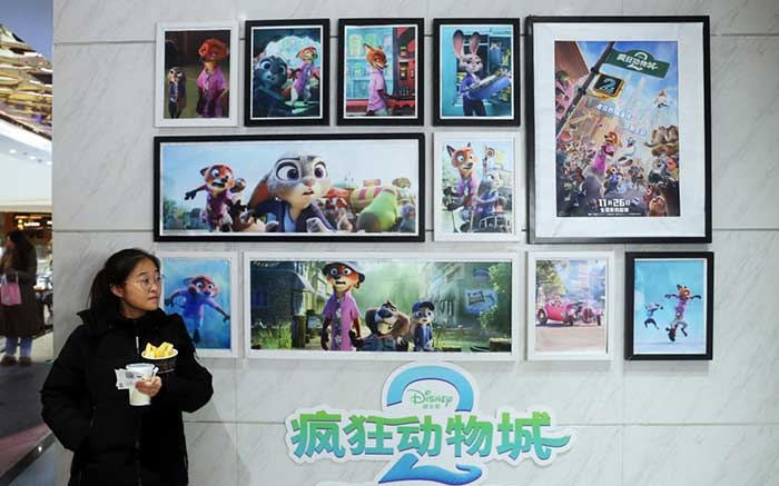 A girl poses for a picture with Zootopia 2 posters in a cinema in Shanghai, Dec. 28, 2025.