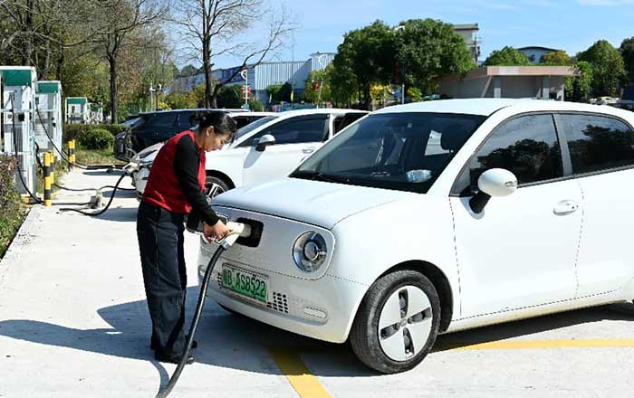 A woman charges her electric vehicle at a public charging station in Dongkou county, Shaoyang, central China's Hunan province. 